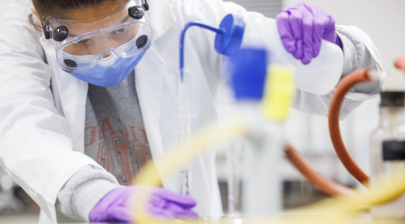 A Pitzer student washes a volumetric flask with solvent during a 化学 lab class